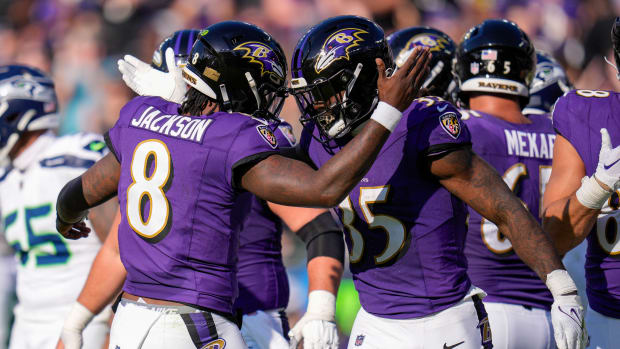 Lamar Jackson reaches out to tap Gus Edwards’s helmet in celebration